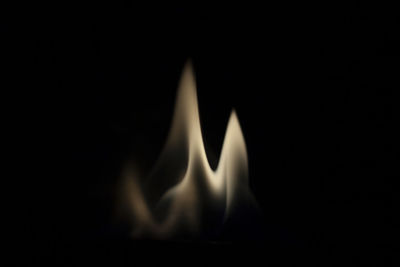 Close-up of lit candle in darkroom