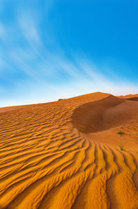 Sand dunes in desert against sky