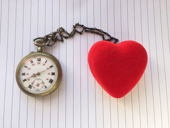 Directly above shot of heart shape tied to pocket watch on white table
