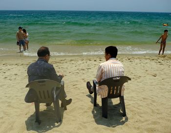 Rear view of people sitting on beach