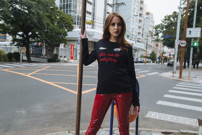 Portrait of young woman standing on road in city