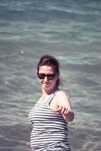 Smiling woman wearing sunglasses enjoying in sea on sunny day