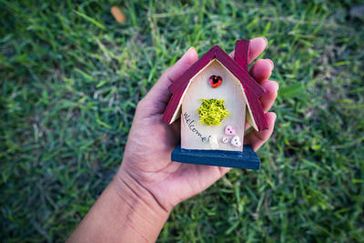 Hand holding small model houses on green grass background, real estate and property concept.
