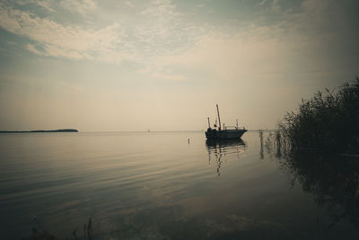 Sailboat in sea against sky during sunset