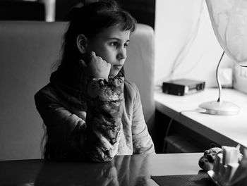 Portrait of a girl sitting on table at home