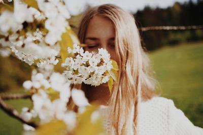 Young woman smelling flowers at park