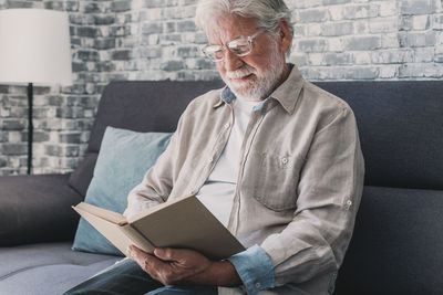 Young man using digital tablet while sitting on sofa at home