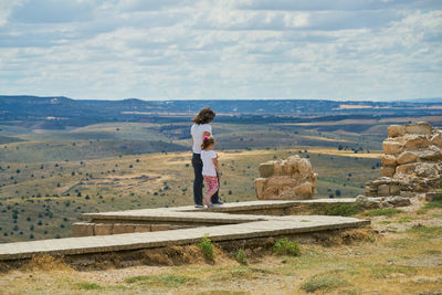 Mother and daughter walk on a footbridge in the mountains