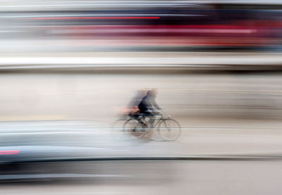 Blurred motion of man riding bicycle on road