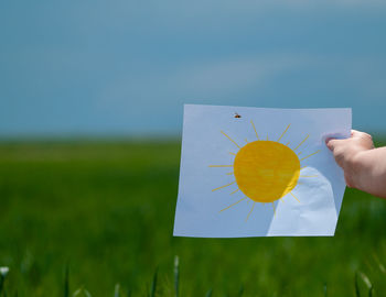 Person holding umbrella on field against sky