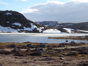 Scenic view of lake by snowcapped mountains against sky