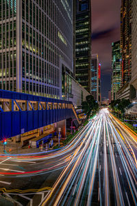 Light trails on city street by buildings at night