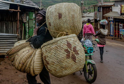 Portrait of man carrying containers on road in city