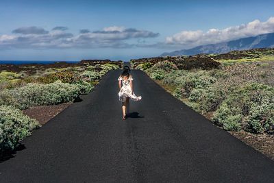 Rear view of woman on road against sky