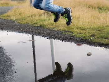 Low section of person with reflection in puddle