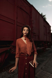 Portrait of woman standing against red wall