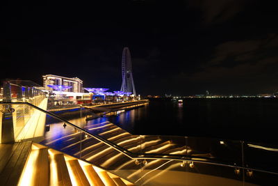 Illuminated bridge over river in city at night