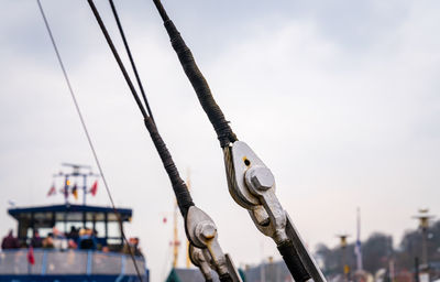 Close-up of cables at harbor against sky
