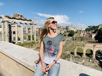 Young woman wearing sunglasses standing against built structure