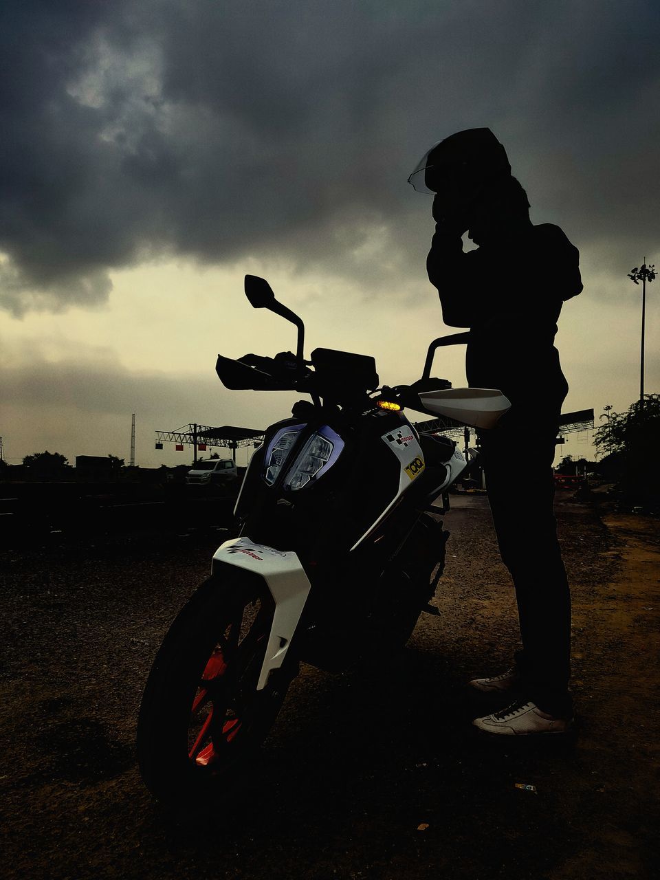 cloud - sky, sky, transportation, mode of transportation, helmet, full length, motorcycle, men, nature, leisure activity, one person, land, standing, lifestyles, land vehicle, side view, real people, silhouette, sunset, outdoors, crash helmet, riding