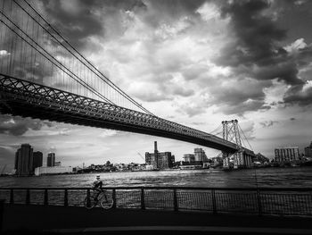 Low angle view of bridge over river against cloudy sky