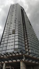 Low angle view of modern building against cloudy sky