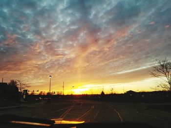 Cars on road against dramatic sky during sunset