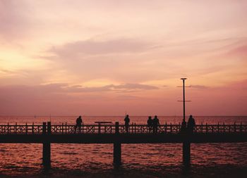 Silhouette people on beach against sky during sunset