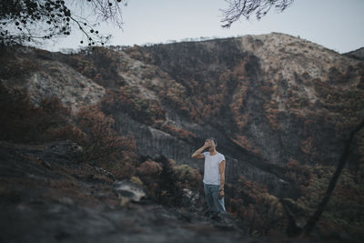 Desperate woman covering face standing in forest