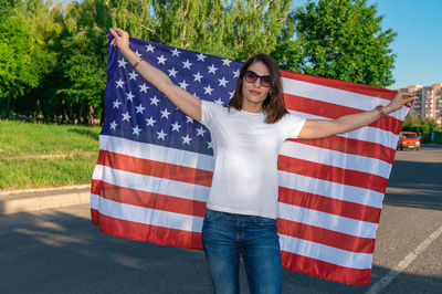 Portrait of smiling pretty young woman holding waving american flag. usa celebrate 4th of july. 