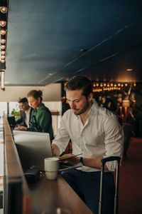 Young businessman using laptop while sitting in hotel