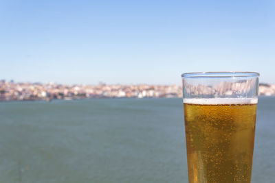 Glass of beer with sea and city in the background