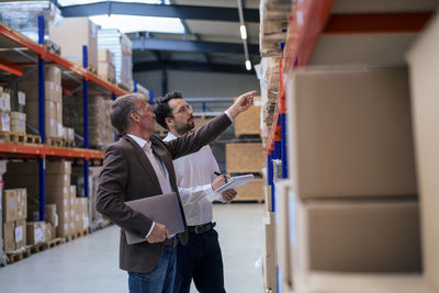 Senior businessman discussing over inventory with colleague at warehouse