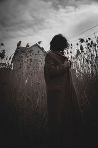 Rear view of woman standing on field against sky