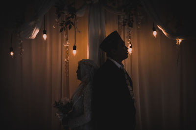 Rear view of man and woman standing in illuminated building