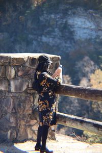 Rear view of woman photographing while standing outdoors