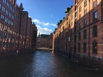 Canal amidst buildings in city against sky