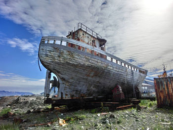 Abandoned boat at beach against sky