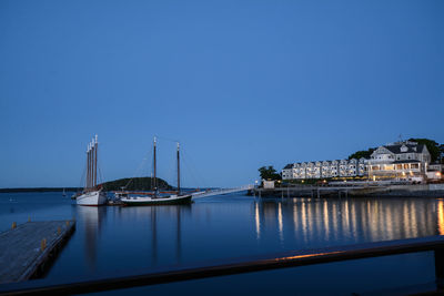 Sailboats moored in sea against clear blue sky