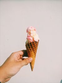 Midsection of person holding ice cream cone against white background