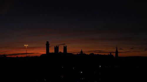 Silhouette of factory against sky during sunset