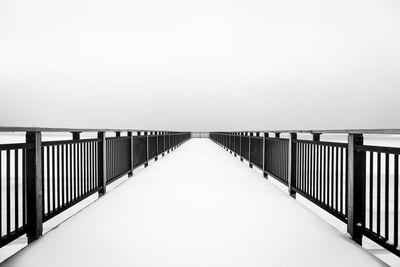 Footbridge over sea against clear sky