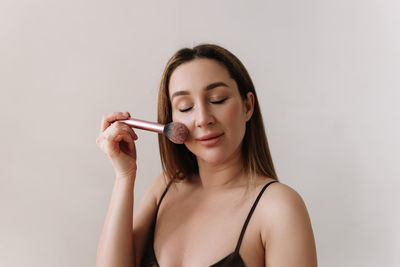 A beautiful natural woman makeup artist preens herself with makeup on a white isolated background