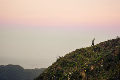 Man standing on mountain against sky during sunset