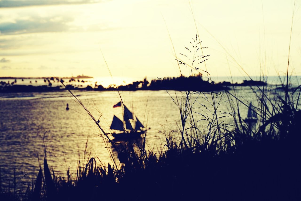 sunset, water, silhouette, nautical vessel, transportation, lake, mode of transport, tranquility, tranquil scene, sky, boat, scenics, nature, beauty in nature, reflection, orange color, river, idyllic, sun, lakeshore