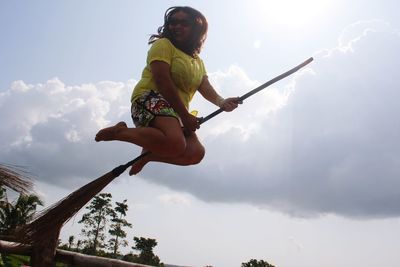 Low angle view of woman holding rope against sky