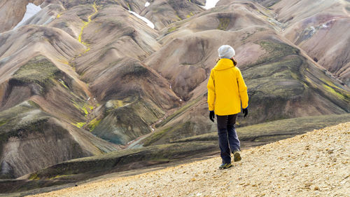 Young woman hiker walking around iceland's highlands and mossy hills