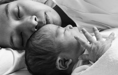 Close-up of mother and cute daughter sleeping on bed at home