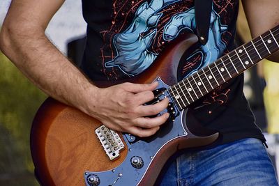 Midsection of man playing guitar outdoor