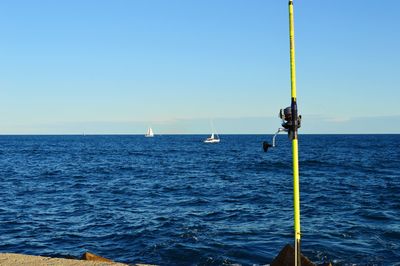 Sailboat in sea against clear blue sky